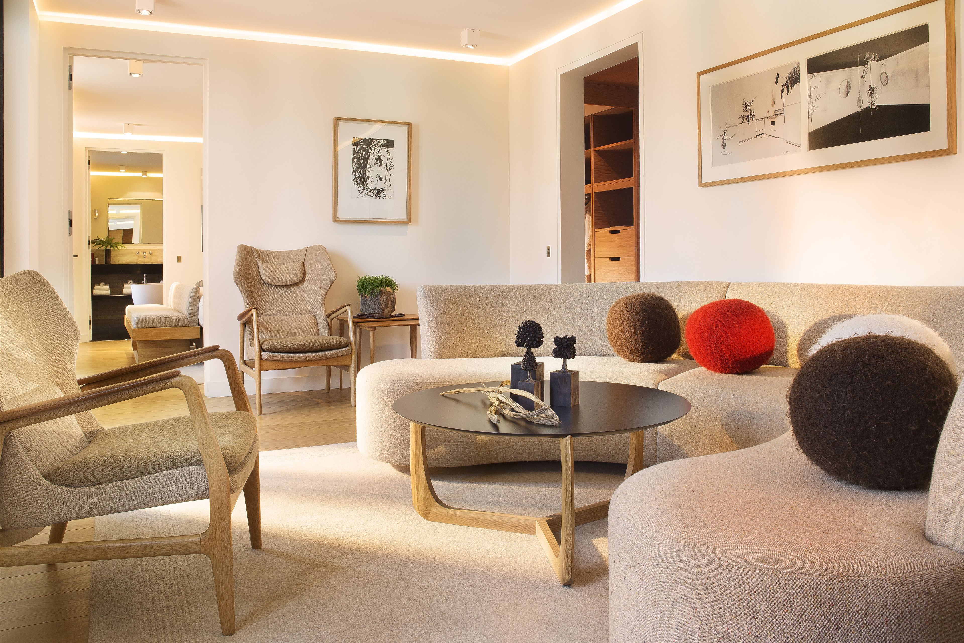 A modern living room with a sofa, armchairs, a coffee table, and a framed picture on the wall.