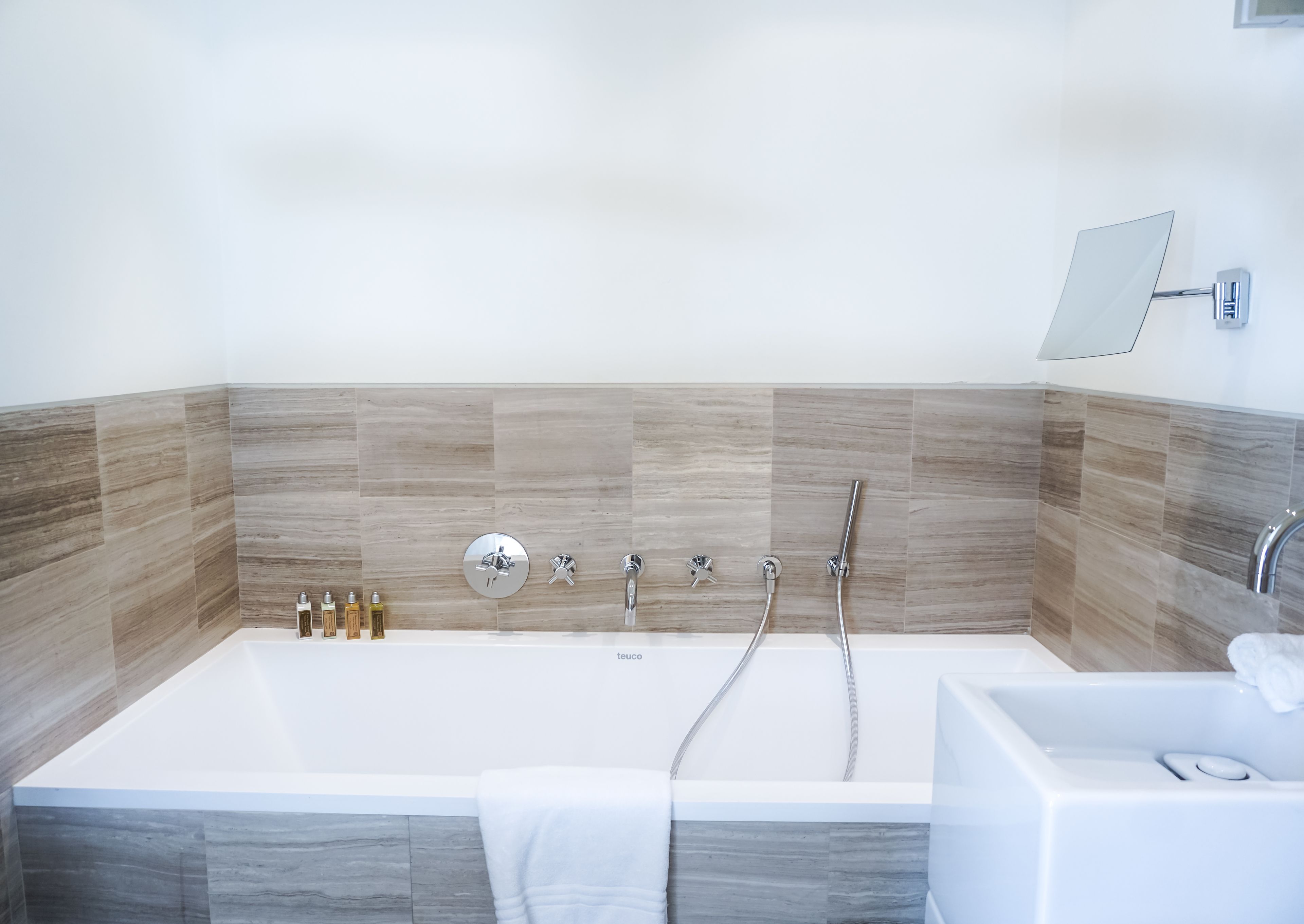 A modern bathroom with a large bathtub, a separate shower area, and a wall-mounted mirror.