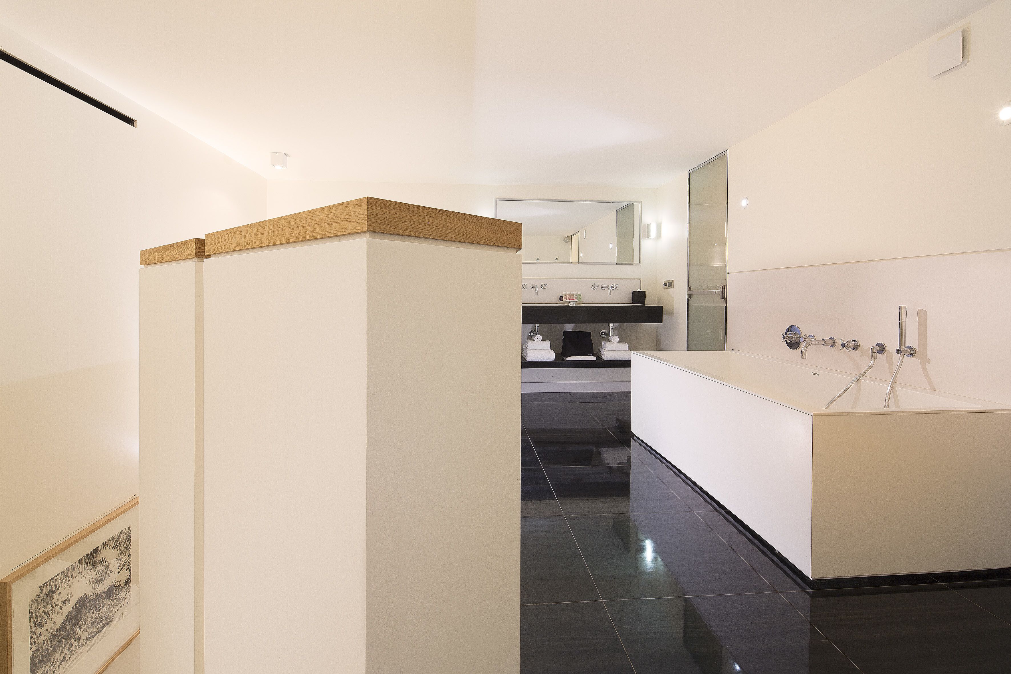 A modern bathroom with a large mirror, a bathtub, and a vanity with a sink.