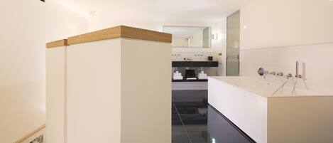 A modern bathroom with a large mirror, a bathtub, and a vanity with a sink.