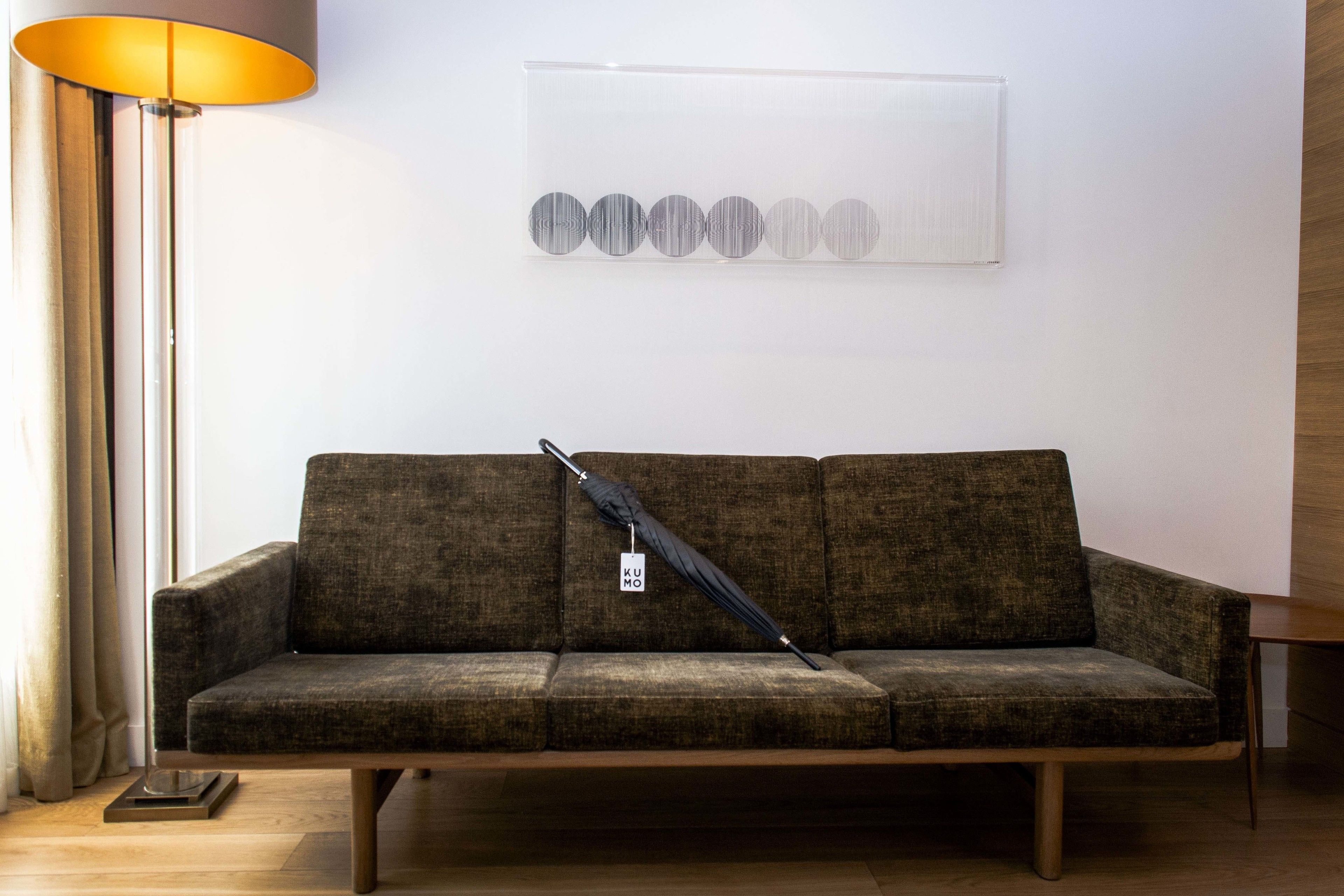 A modern living room with a sofa, a floor lamp, and a wall art piece.