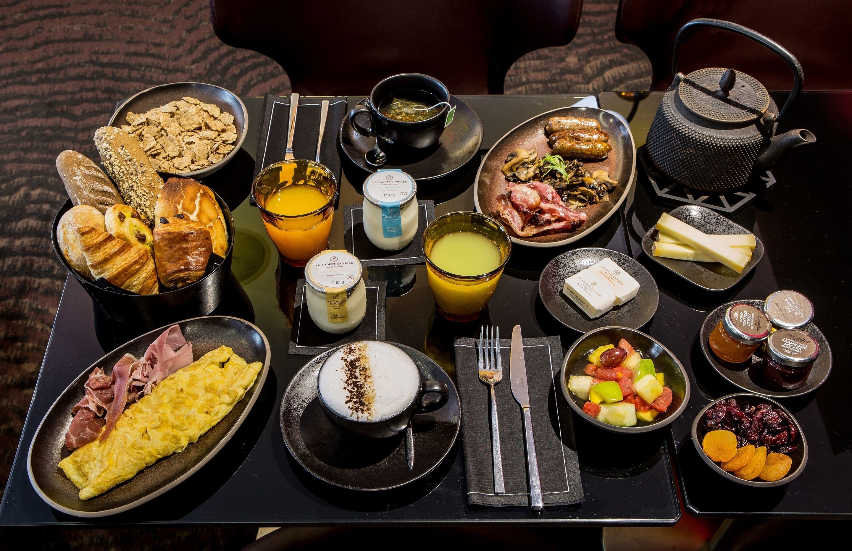 Een ontbijttafel met verschillende soorten eten, zoals brood, eieren, fruit en drankjes.