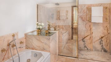Un baño moderno con ducha acristalada, bañera y paredes de mármol.