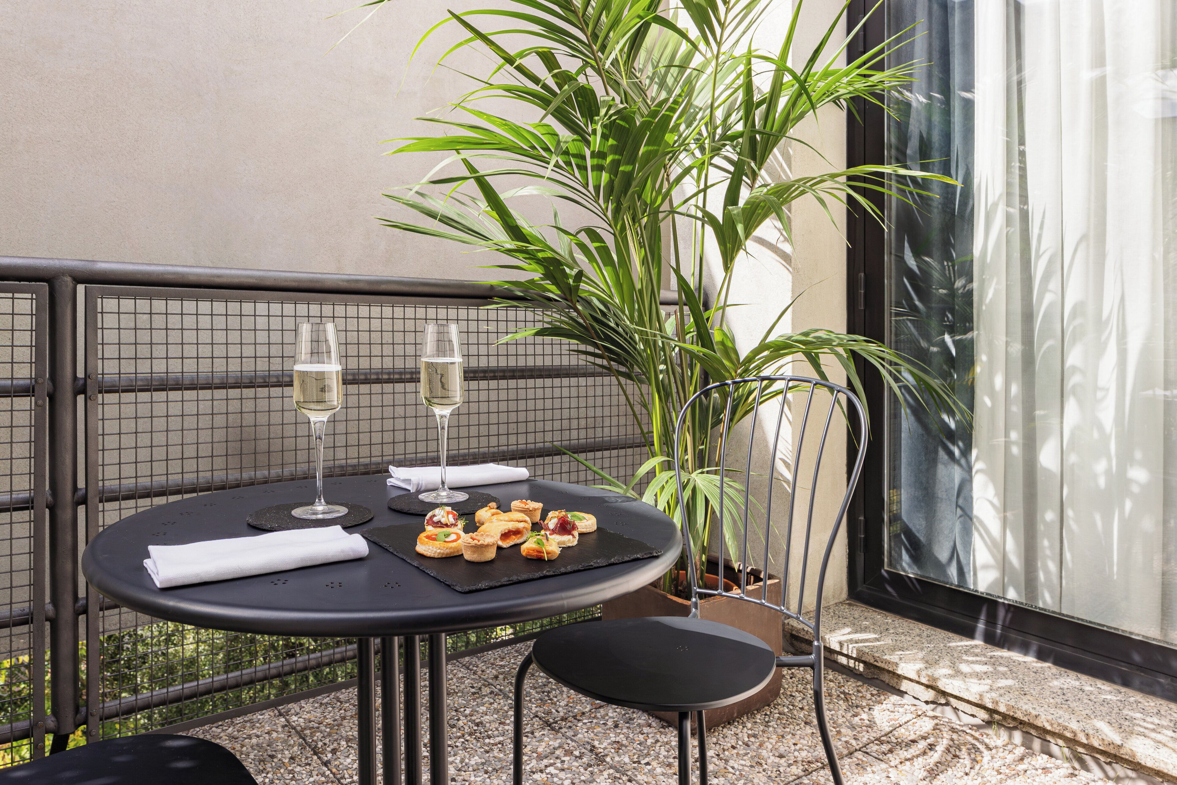 A round table with a black tablecloth, two wine glasses, a folded napkin, and a plate of appetizers.