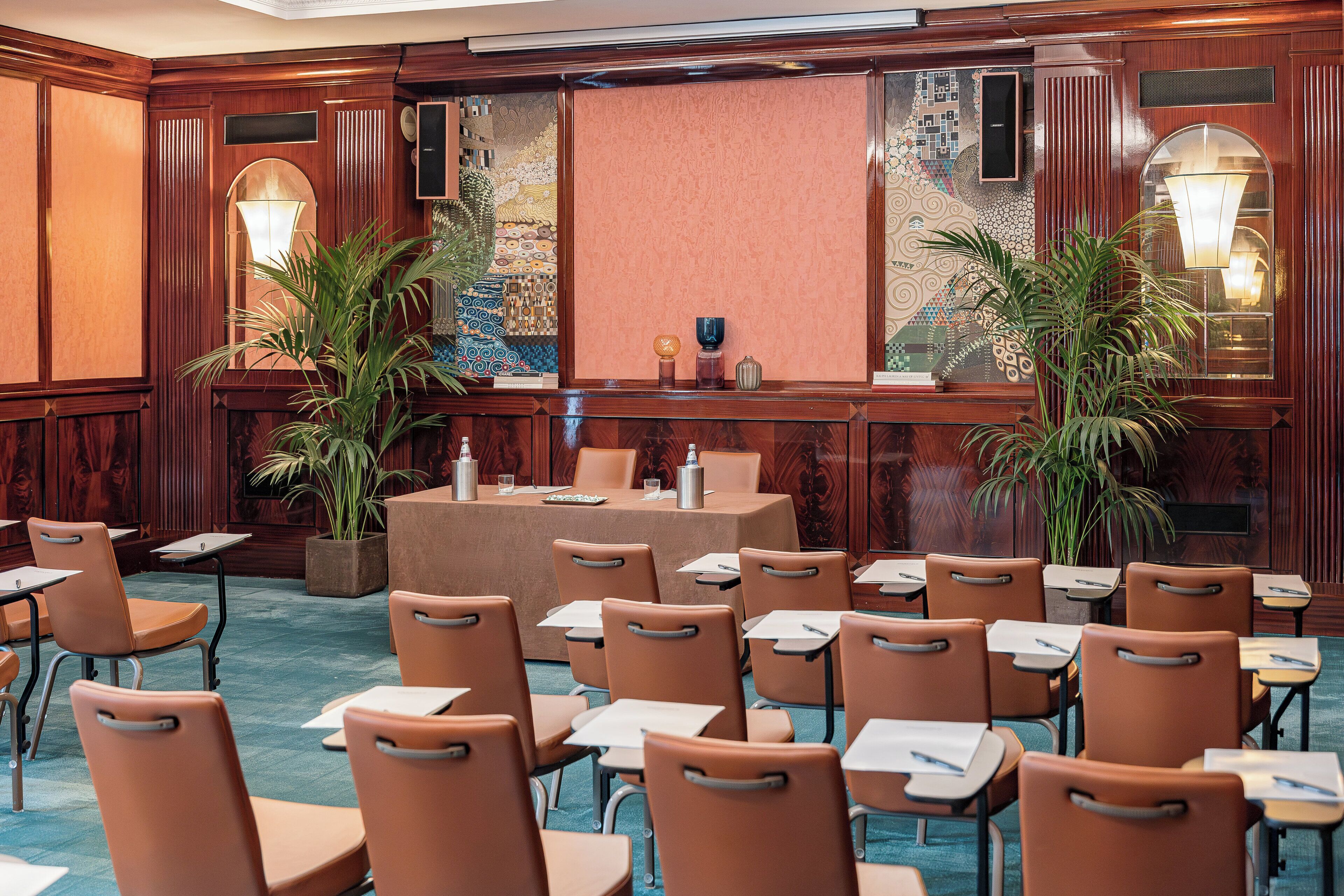 A conference room with a long table, multiple chairs, and two potted plants.