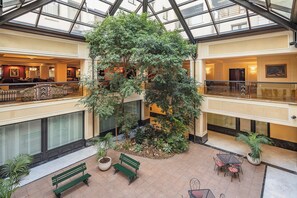 Un amplio atrio con una gran palmera interior, zonas de estar y un techo alto con tragaluces.