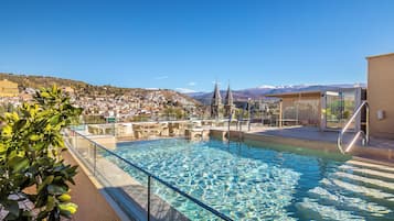 Een seizoensgebonden buitenzwembad en ligstoelen