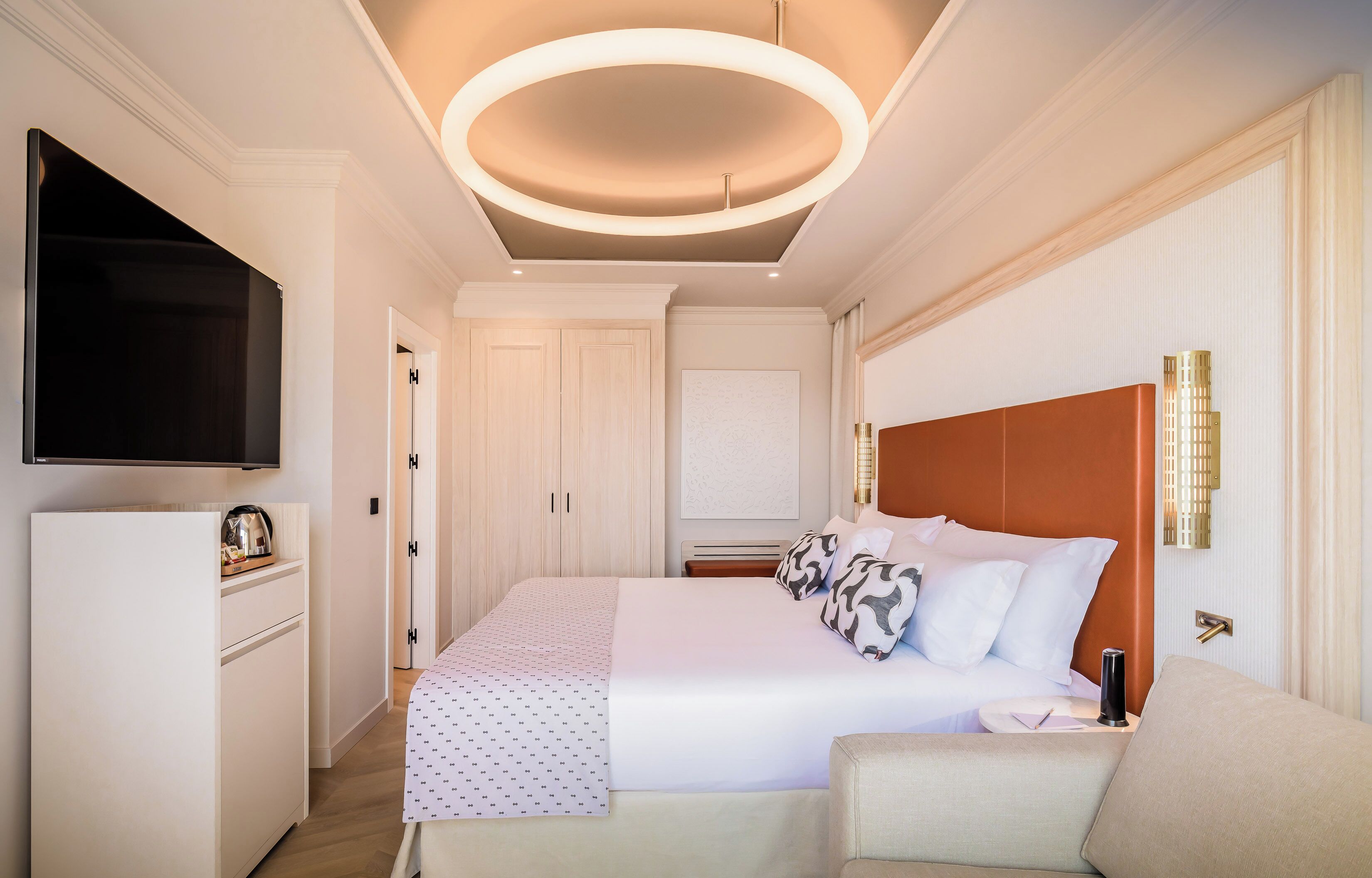 Una habitación de hotel moderna con una cama grande, un televisor de pantalla plana, un escritorio y una silla.