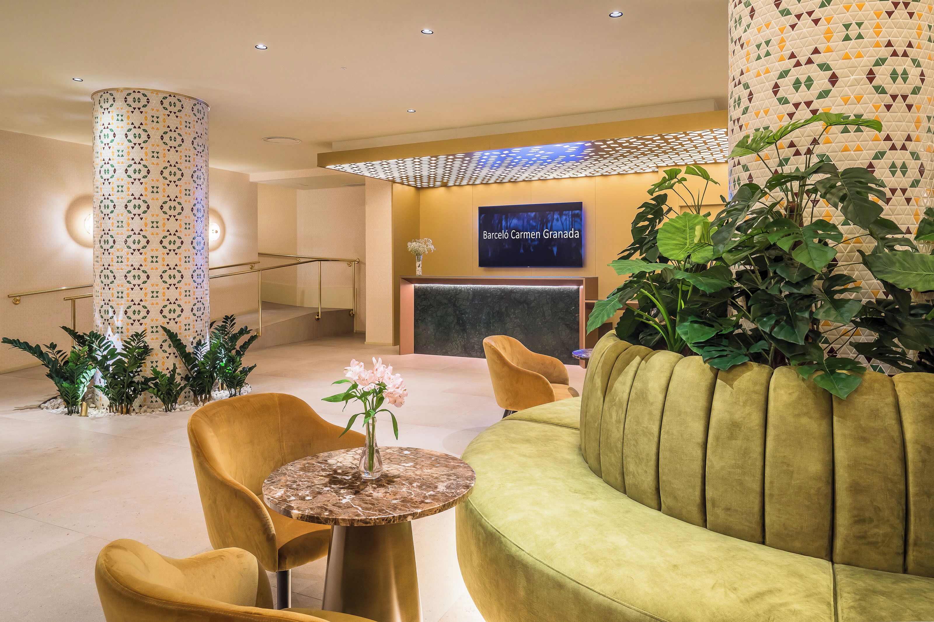 A modern lobby with a reception desk, a green sofa, and a round table with a vase of flowers.