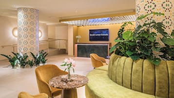 A modern lobby with a reception desk, a green sofa, and a round table with a vase of flowers.