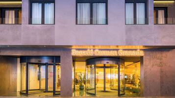 A hotel entrance with a revolving door, glass doors, and a sign reading "Barcelona Carmen Granada".