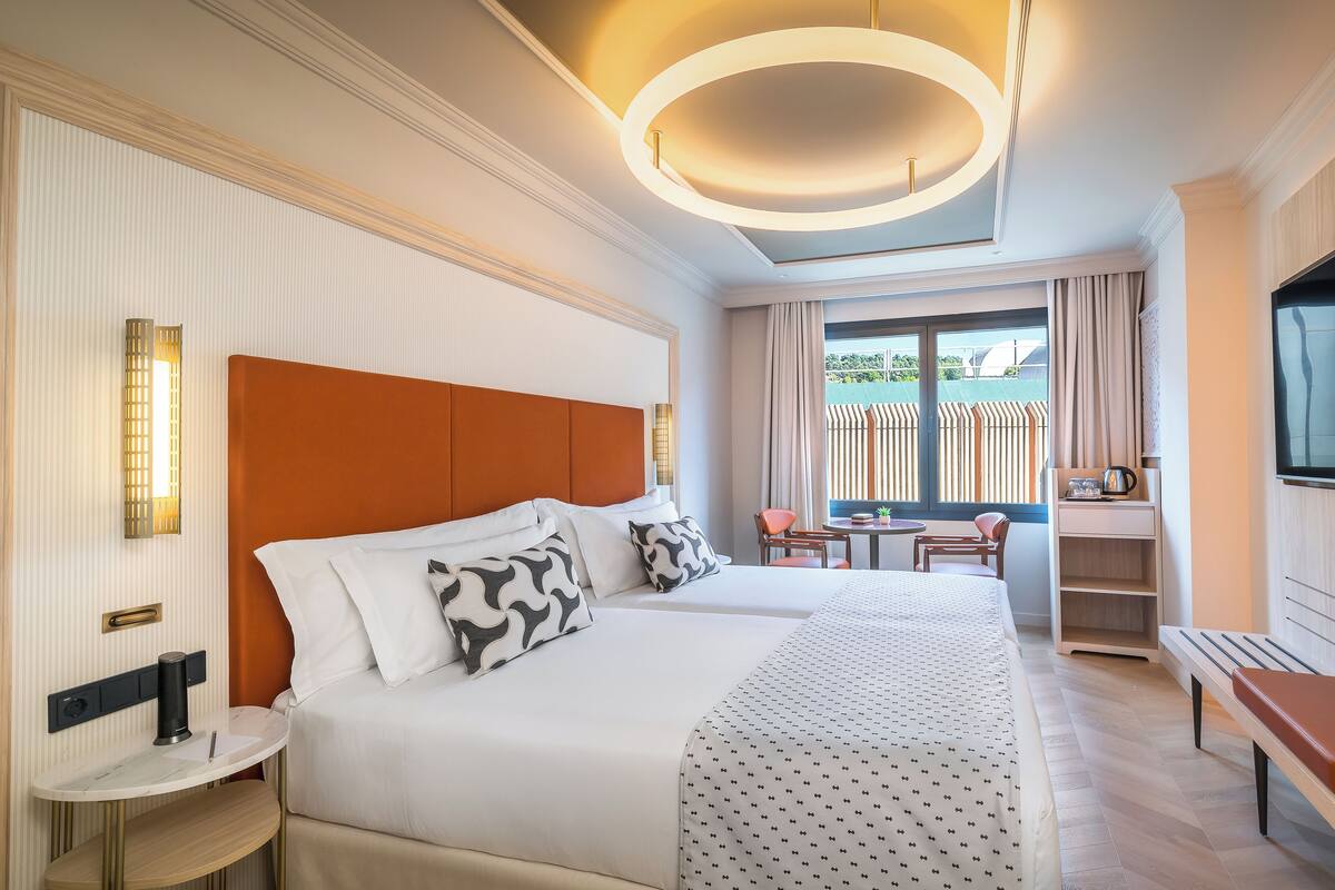 A hotel room with a large bed, a desk, a chair, and a TV.