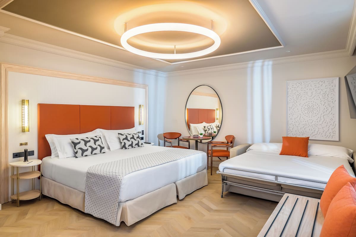 A modern hotel room with a large bed, a desk, and a chair.