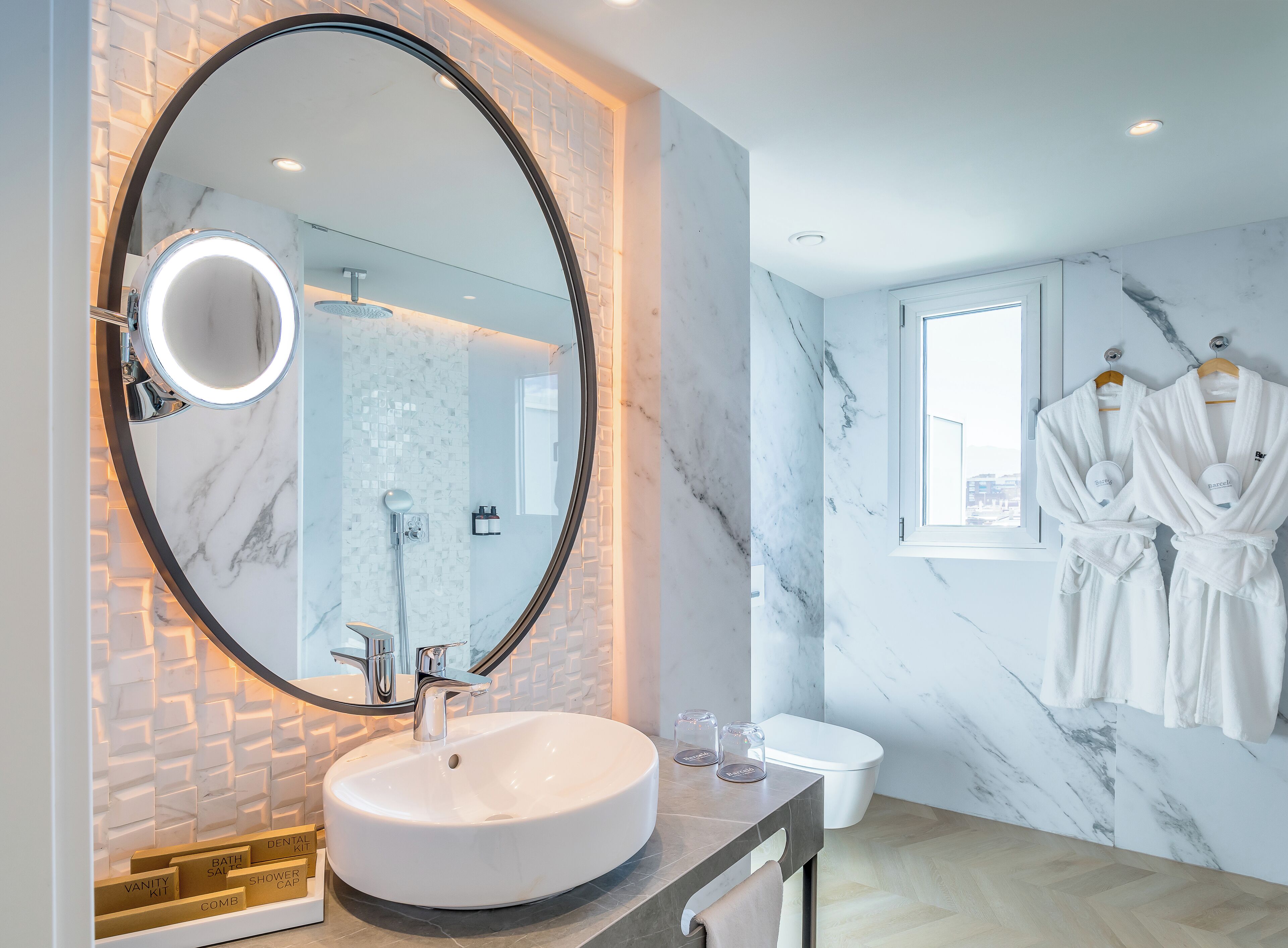 A modern bathroom with a large mirror, a round sink, and a shower area.