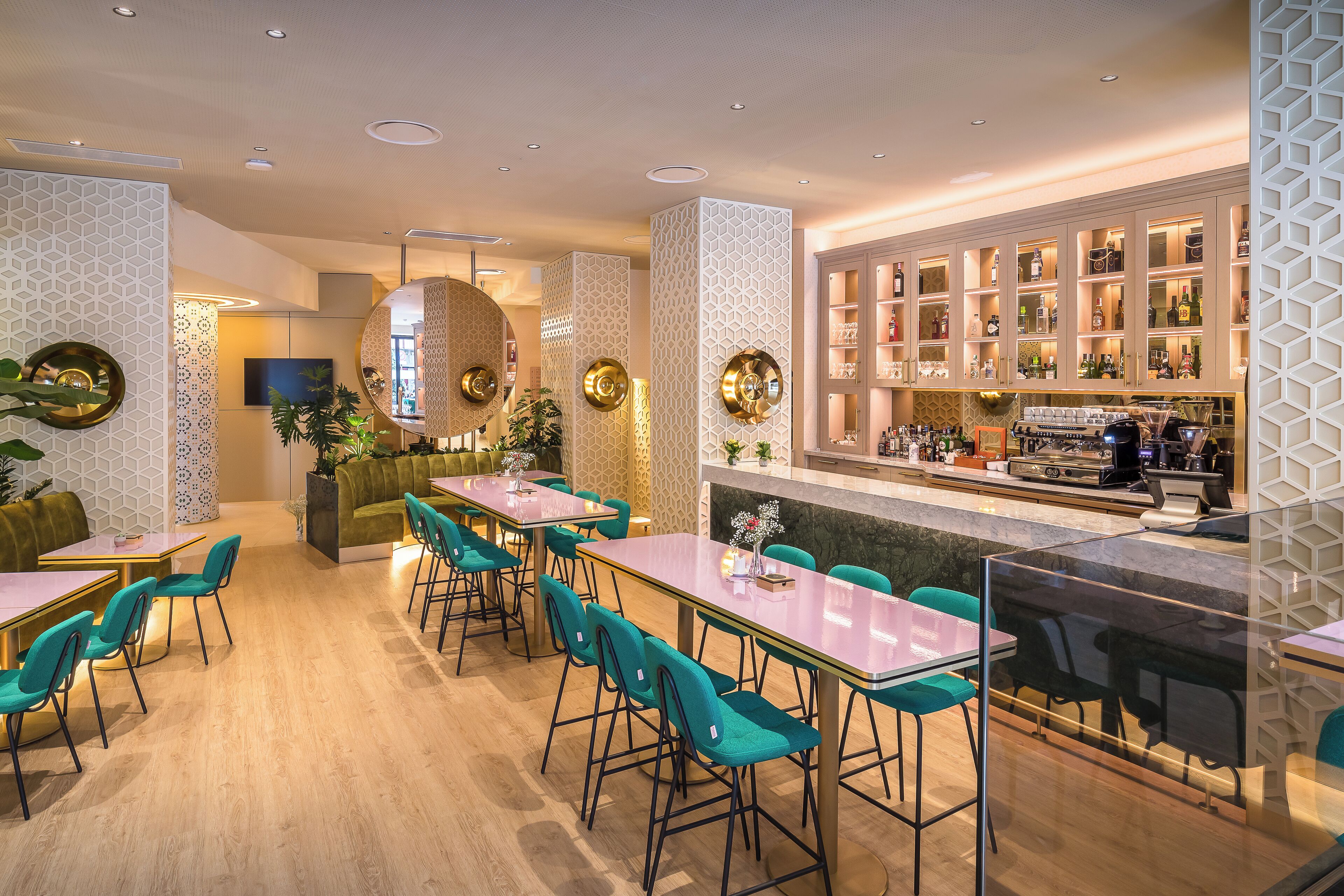 A modern bar area with a counter, bar stools, and a variety of liquor bottles.