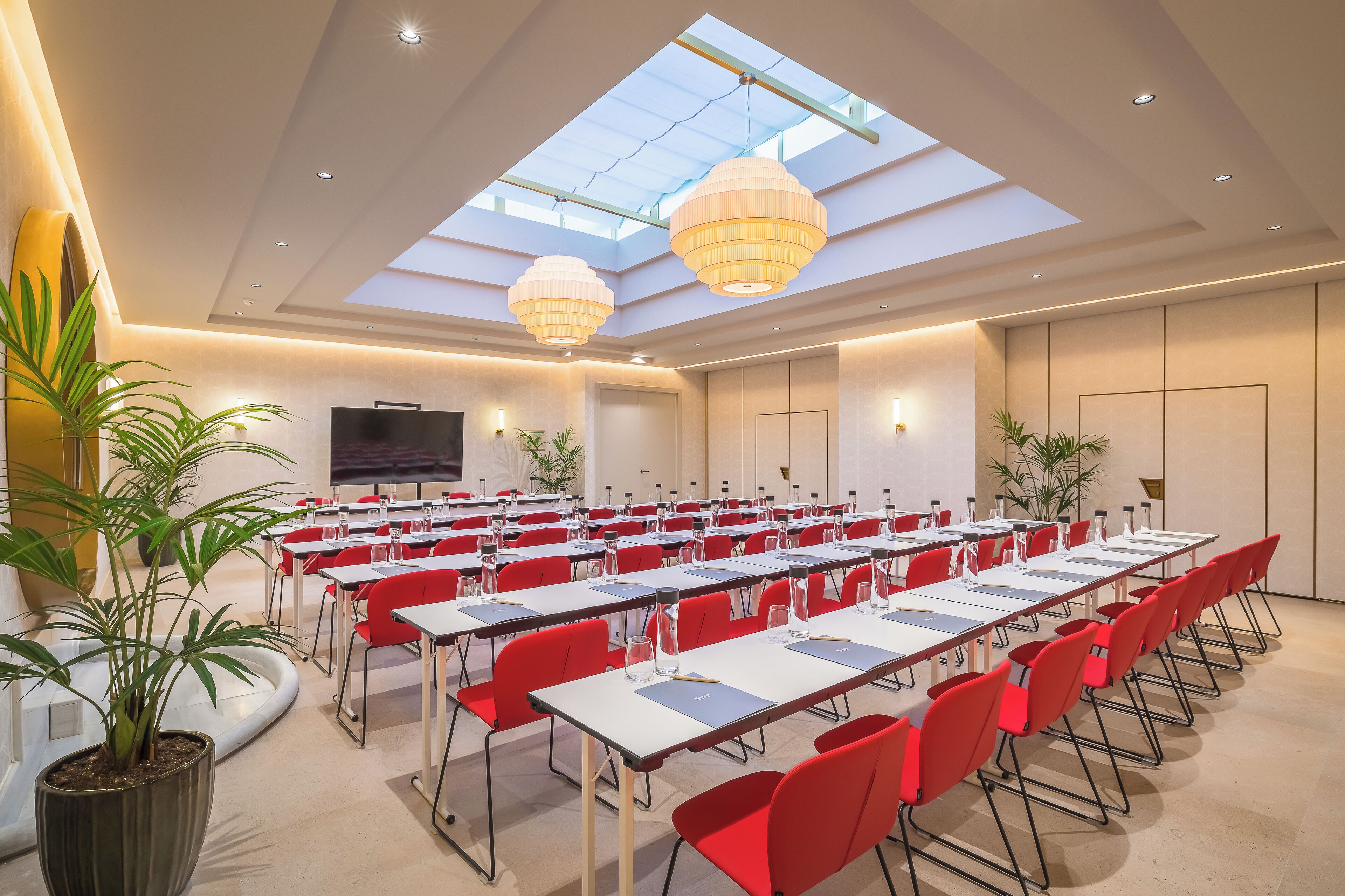 Une salle de conférence équipée de tables, de chaises et de plantes en pot.
