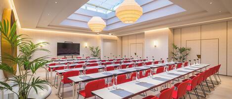 Une salle de conférence équipée de tables, de chaises et de plantes en pot.