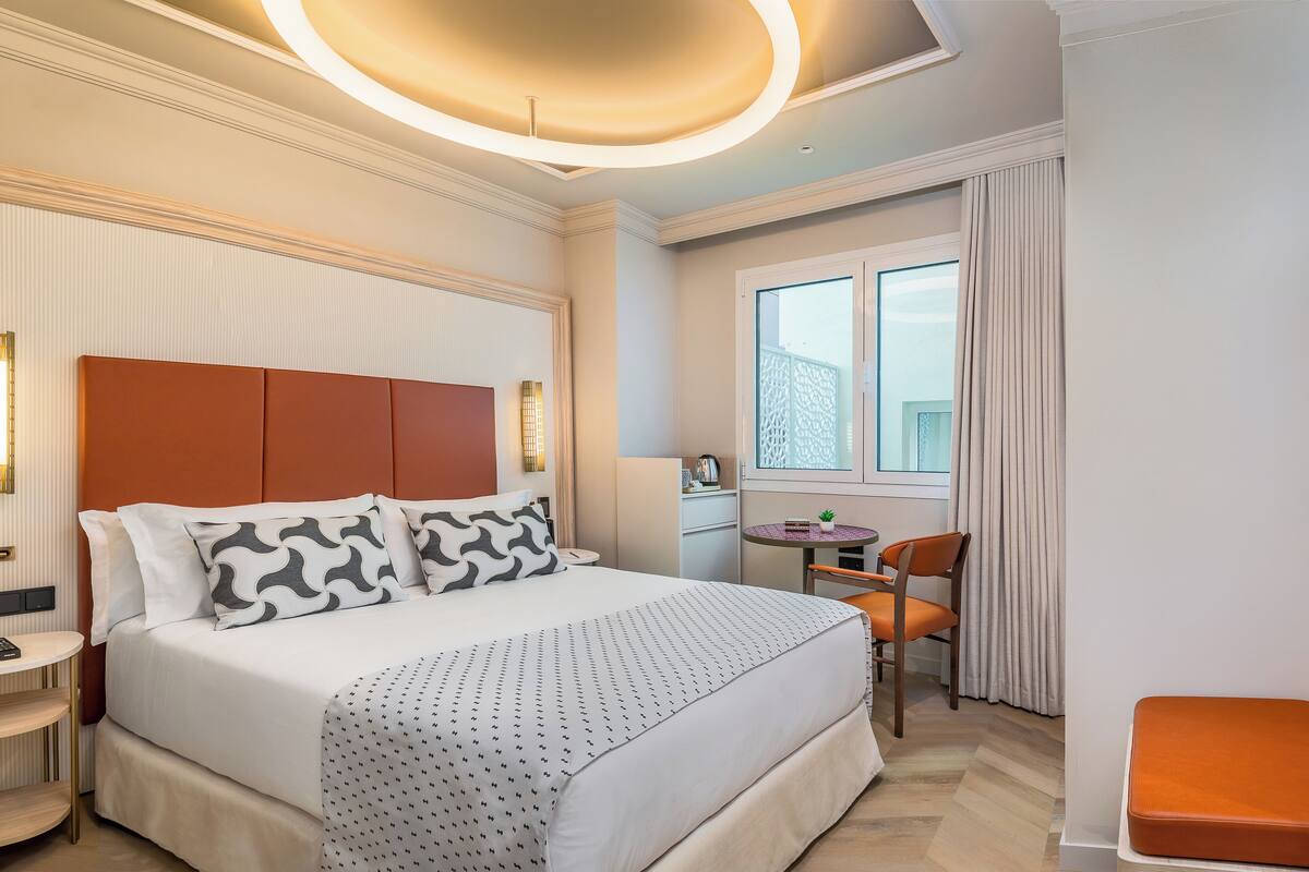 A modern hotel room with a large bed, a desk, and a chair.