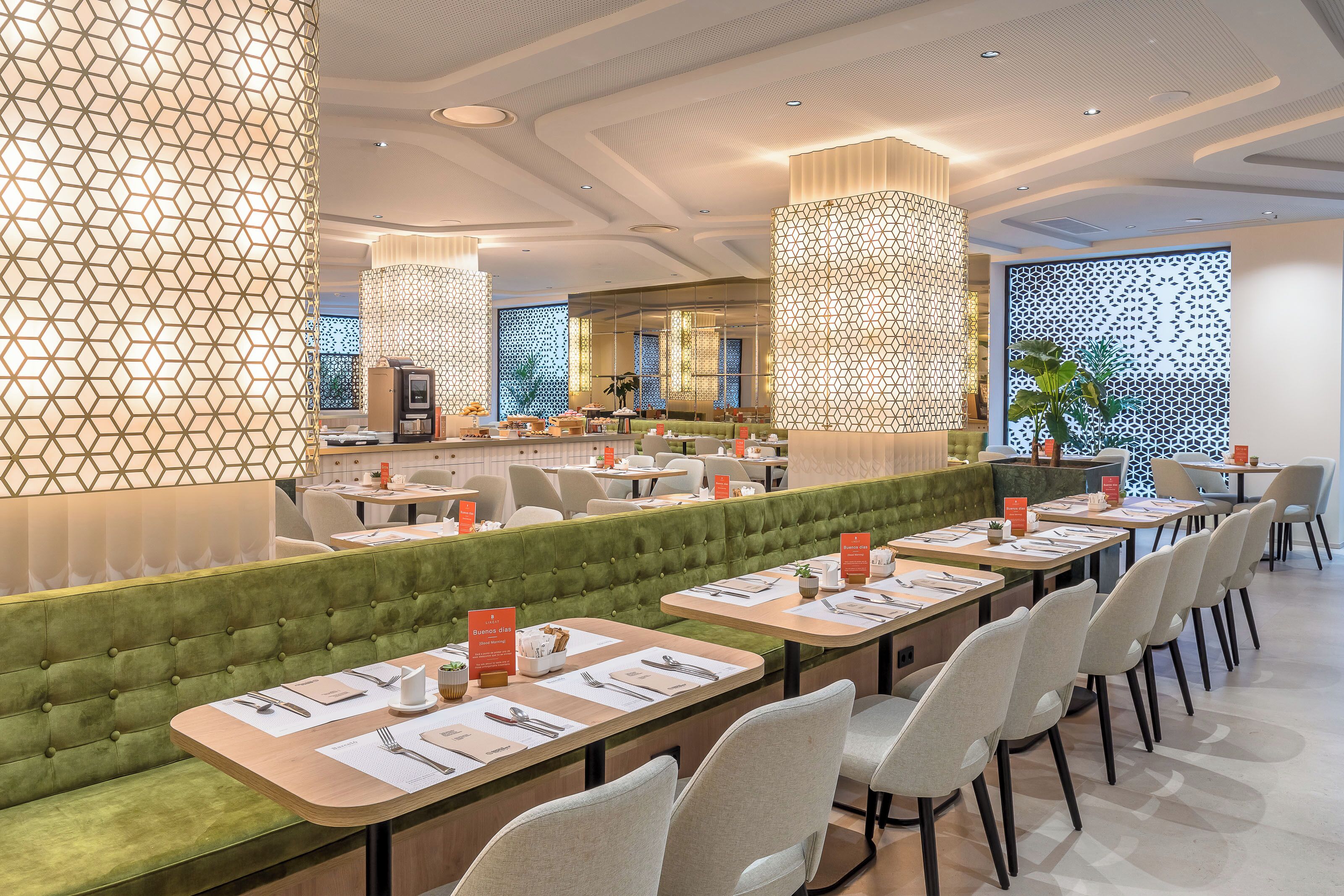 Un restaurante moderno con un área de asientos con bancos acolchados de color verde, varias mesas con menús y paneles decorativos en las paredes.
