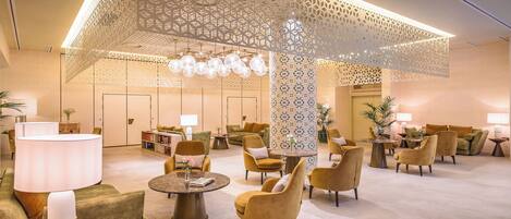A spacious lobby with modern furniture, a decorative ceiling, and ambient lighting.