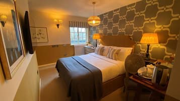 A hotel room with a bed, bedside lamps, a desk with a chair, and a window.