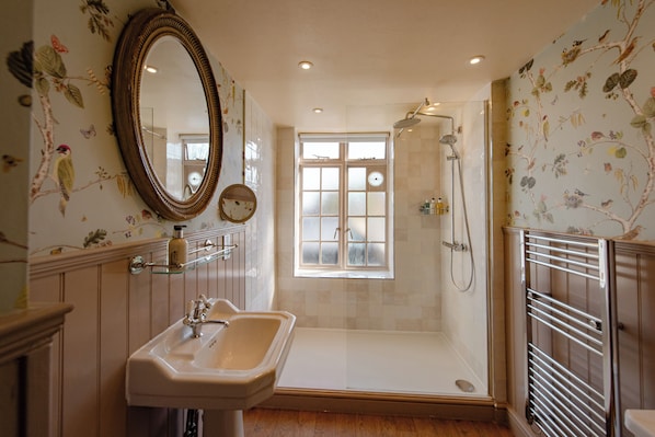 Ein Badezimmer mit Waschbecken, Spiegel, Dusche und einem Fenster mit Milchglas.