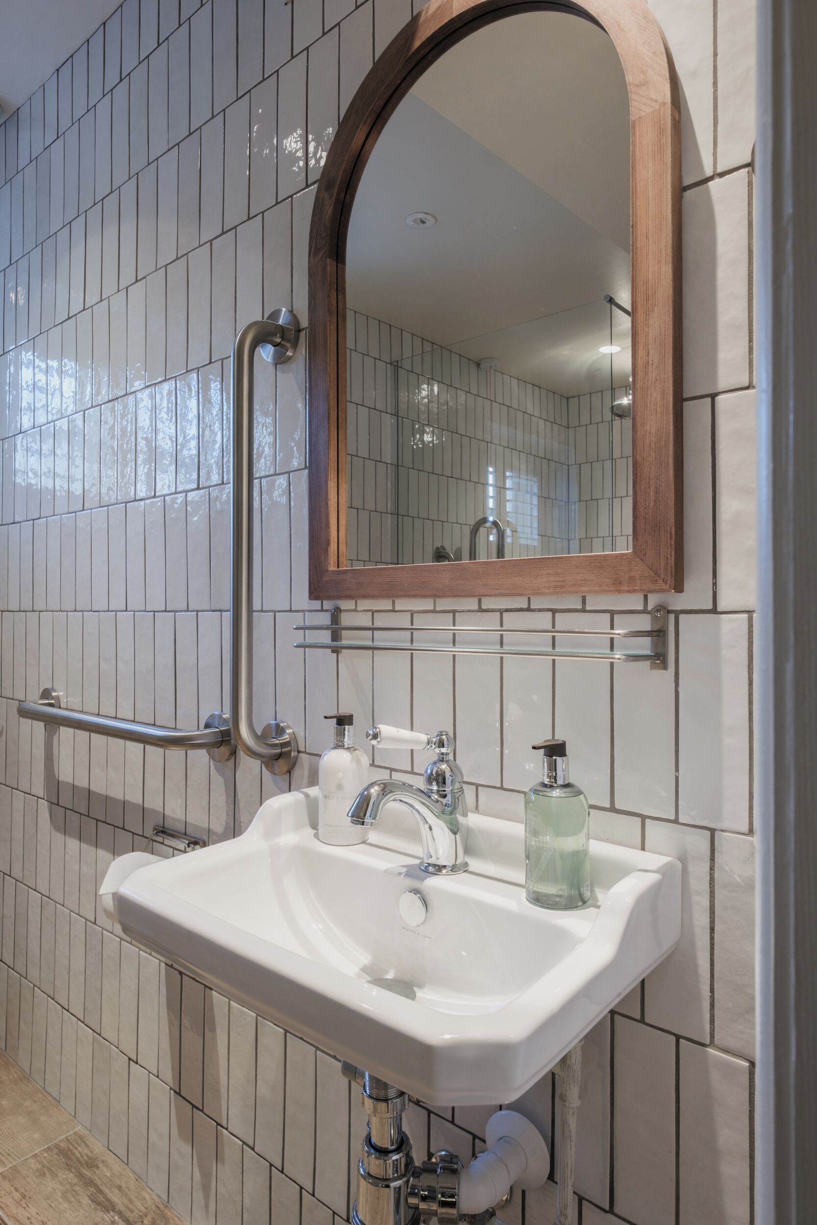Un baño con lavamanos blanco, un espejo con marco de madera y una barandilla.