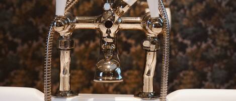 Un baño con sistema de ducha de estilo vintage, que incluye un cabezal de ducha de mano y un grifo empotrado con manguera flexible.