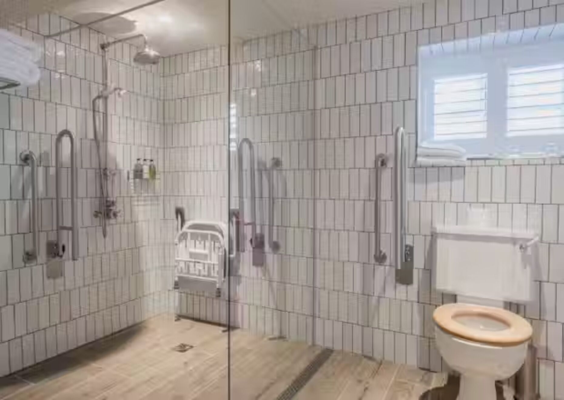 A bathroom with a shower, toilet, and a glass partition.
