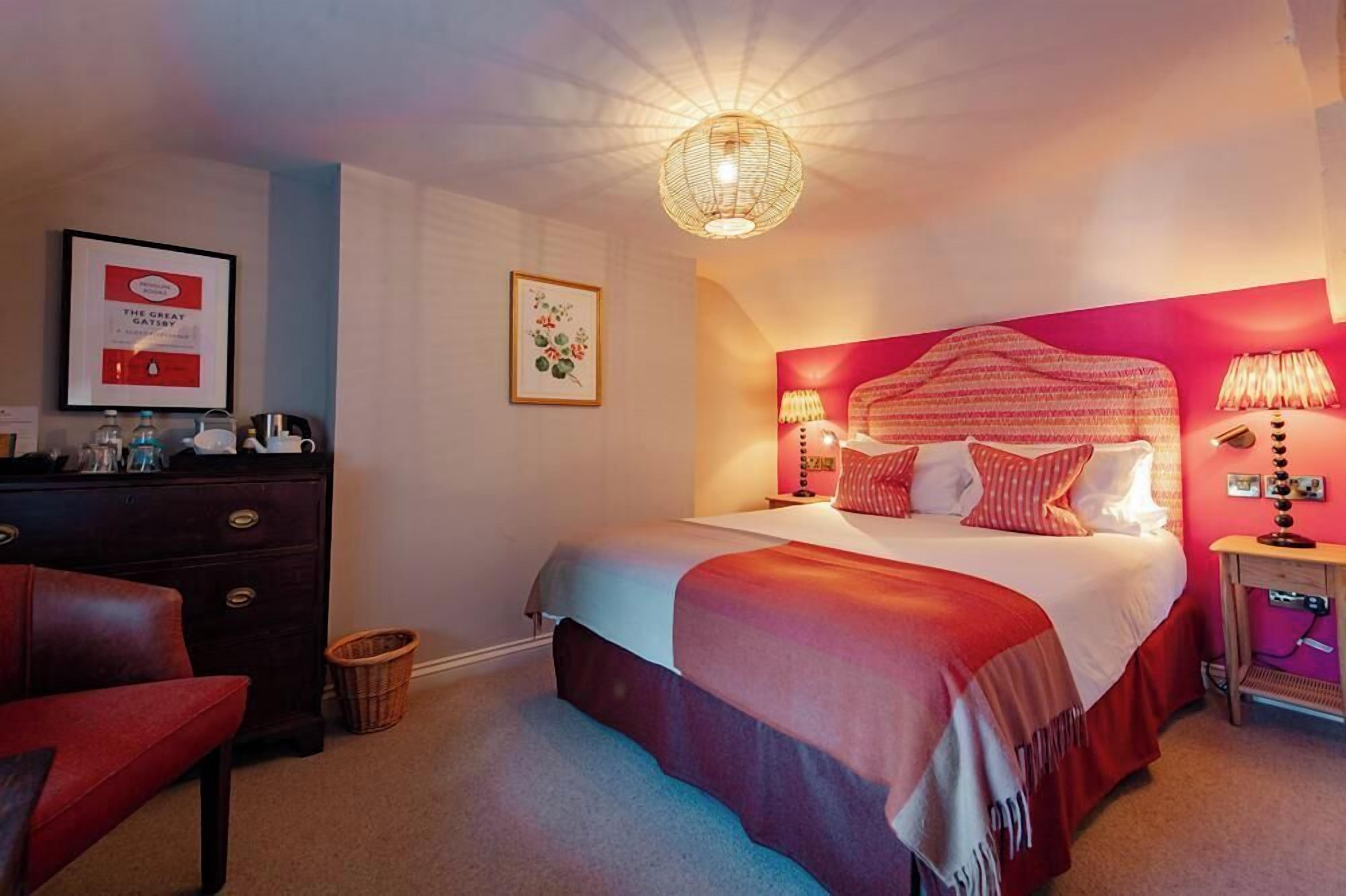 Une chambre à coucher avec un grand lit, une commode, une chaise et un tableau encadré au mur.
