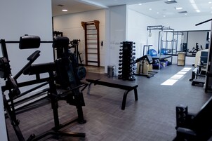 A gym with various exercise equipment, a wooden ladder, and a mirrored wall.
