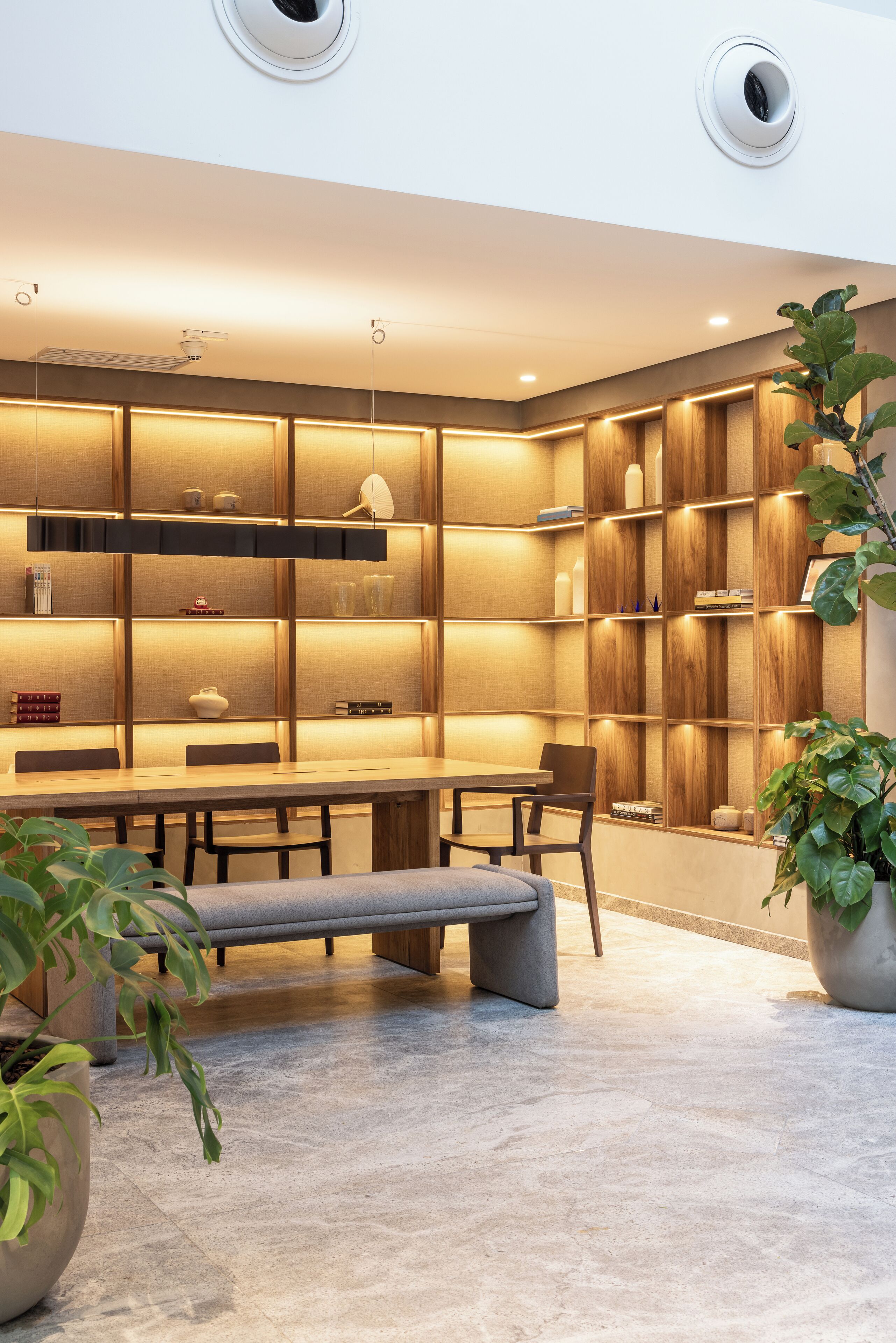 Un interior moderno con comedor, estanterías de madera e iluminación empotrada.