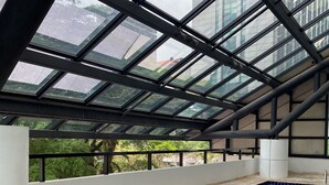 Un área de estar al aire libre cubierta con piscina, que incluye una mesa con bebidas y un menú, y sillas de mimbre.