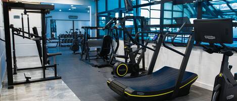 A gym with exercise equipment, large windows, and a blue wall.