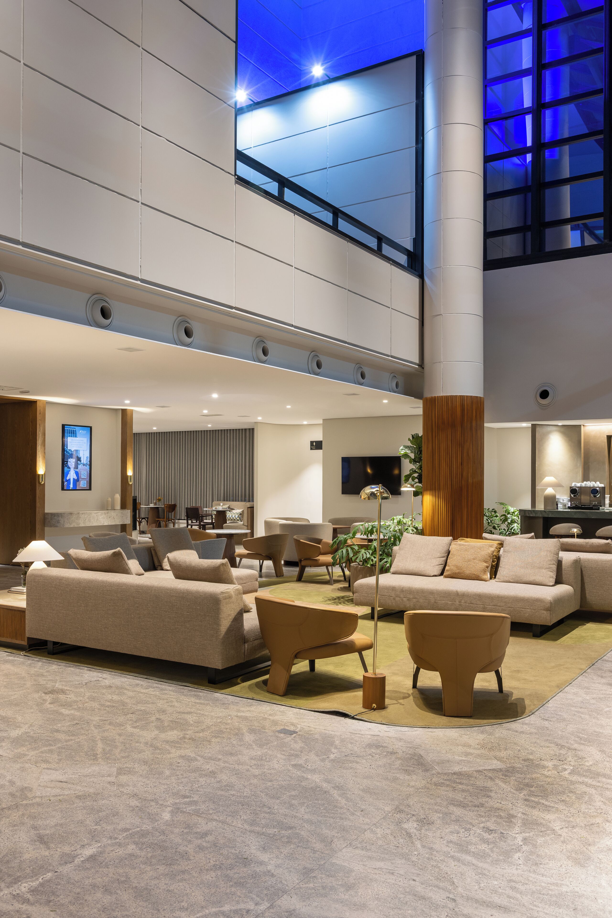 Eine geräumige Lobby mit hoher Decke, einer großen Säule und einer Sitzecke mit Sofas und Sesseln.
