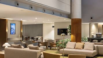Eine geräumige Lobby mit hoher Decke, einer großen Säule und einer Sitzecke mit Sofas und Sesseln.