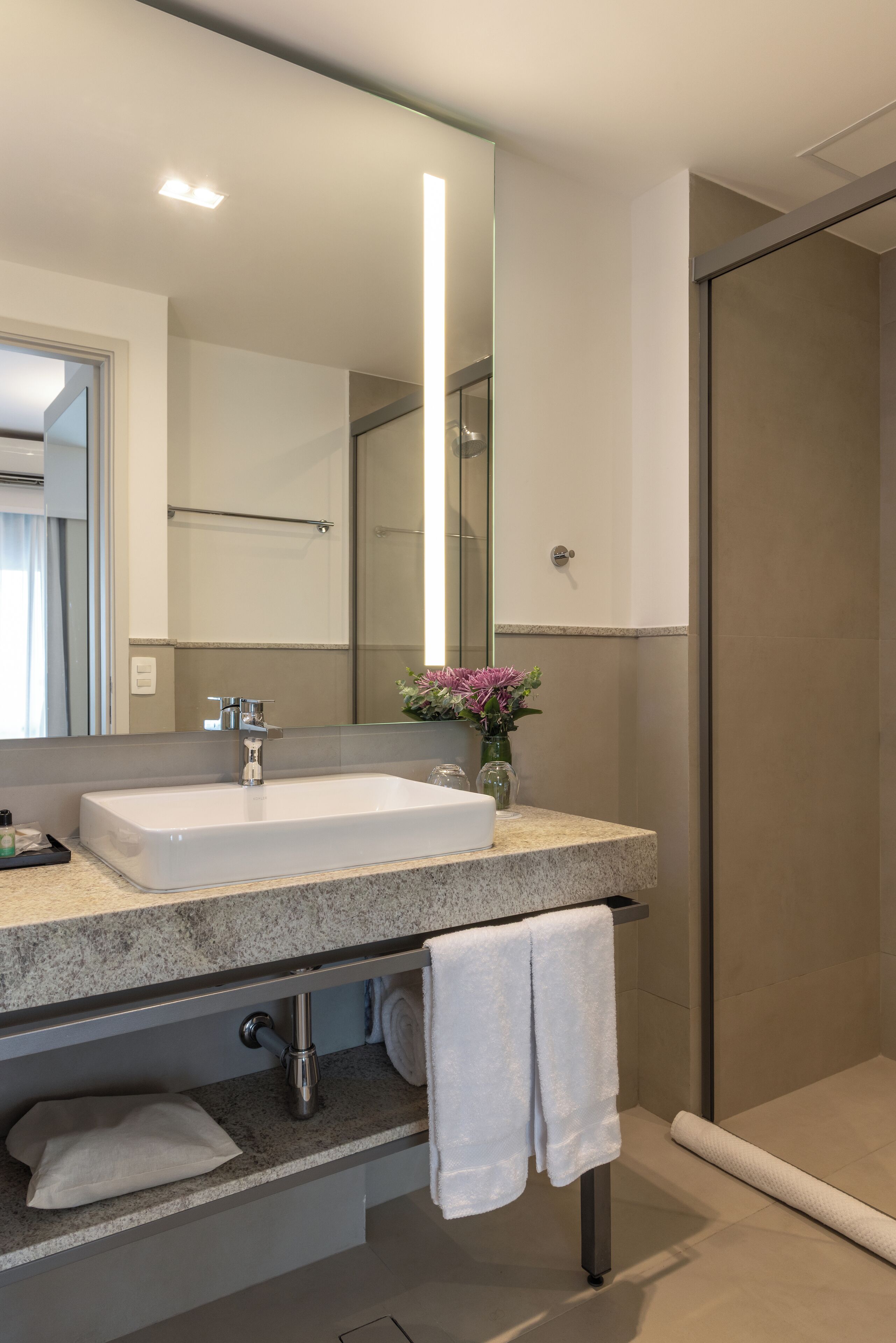A modern bathroom with a large mirror, a sink, and a shower area.