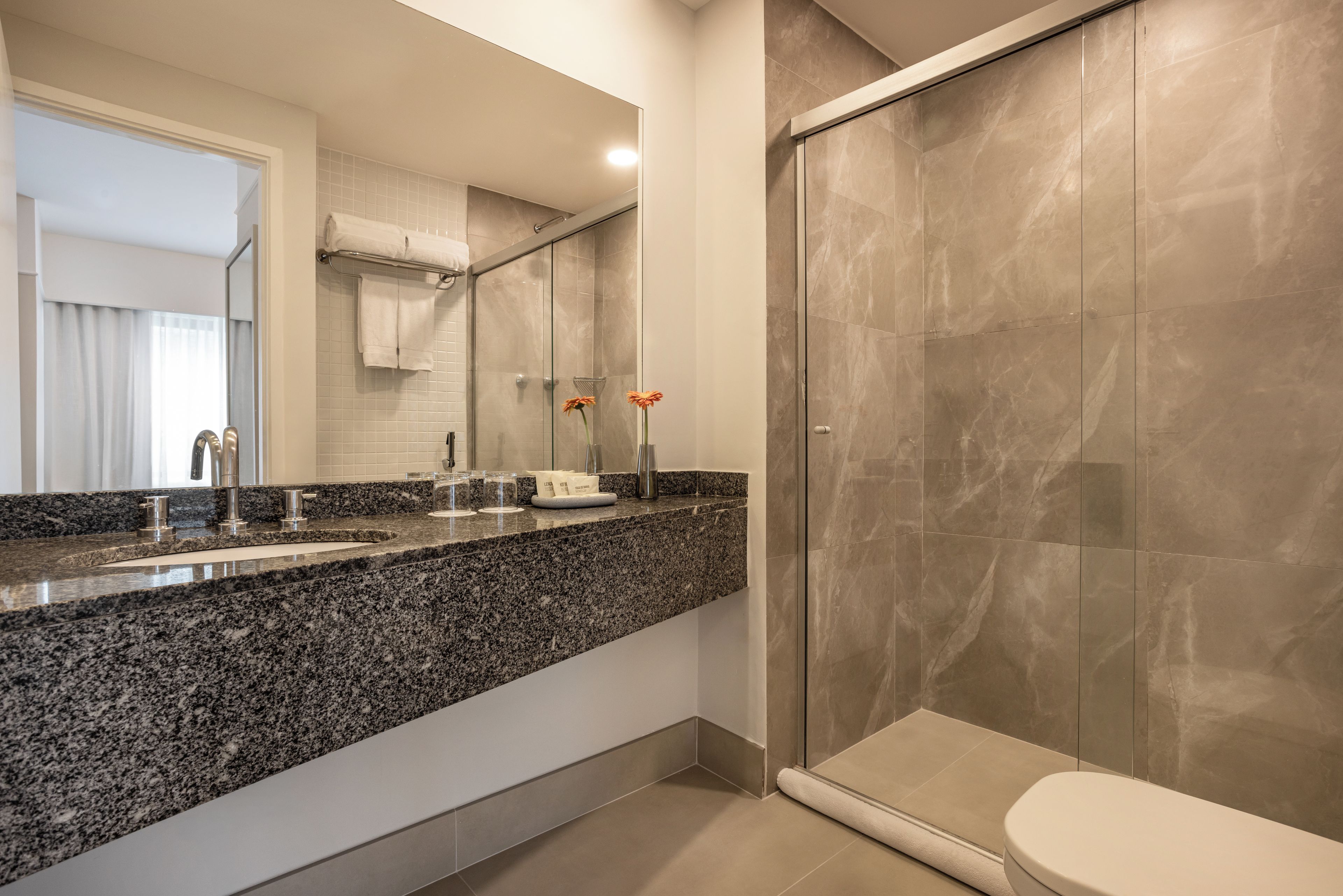 Ein modernes Badezimmer mit einer Granittafel, einer Duschkabine aus Glas und einer Toilette.