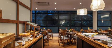 Un ristorante con un bancone in legno, sedie e lampade a sospensione.