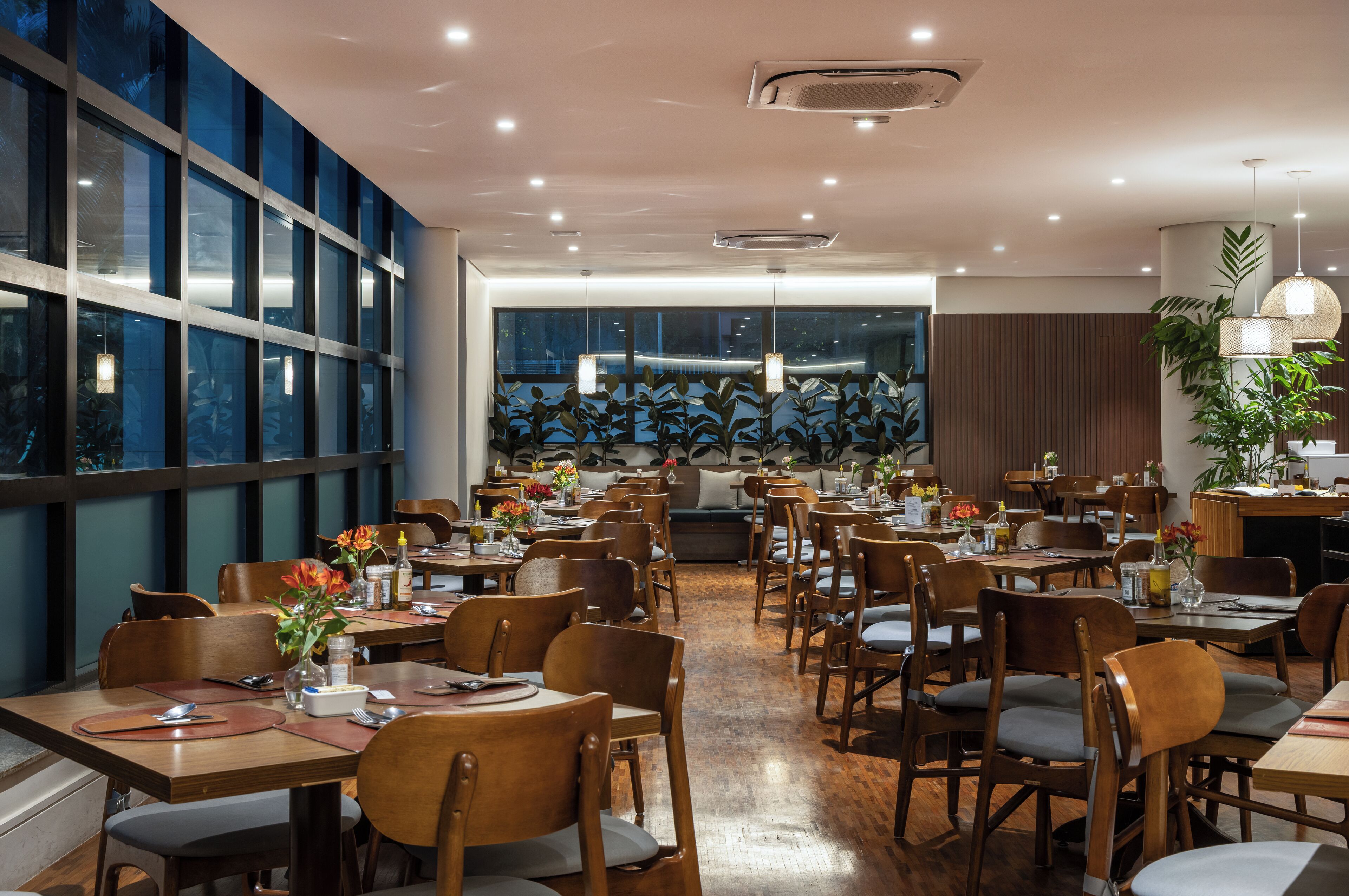 A spacious dining area with multiple tables and chairs, large windows, and a modern interior design.