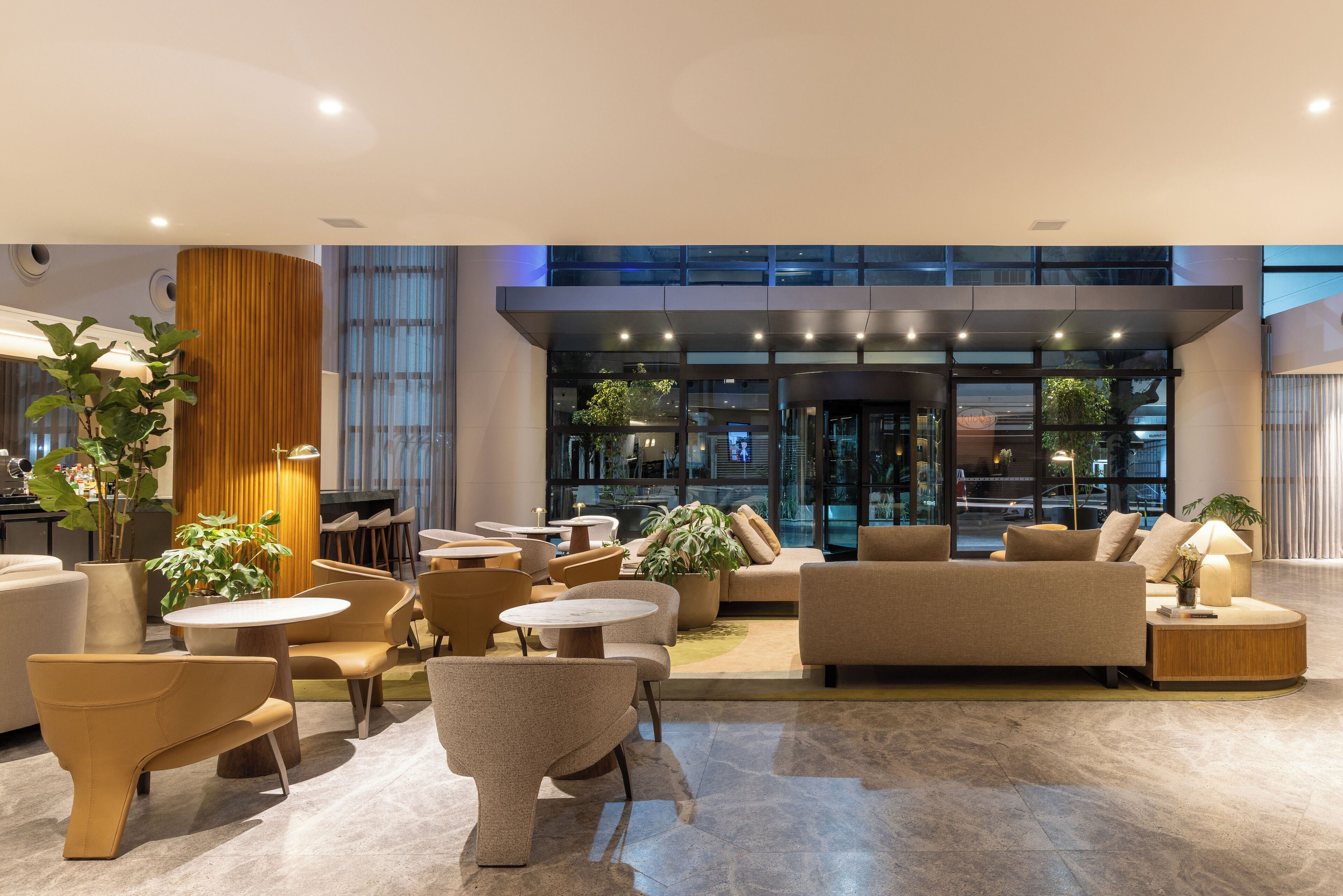 A modern lobby with seating areas, a reception desk, and a view of the entrance.