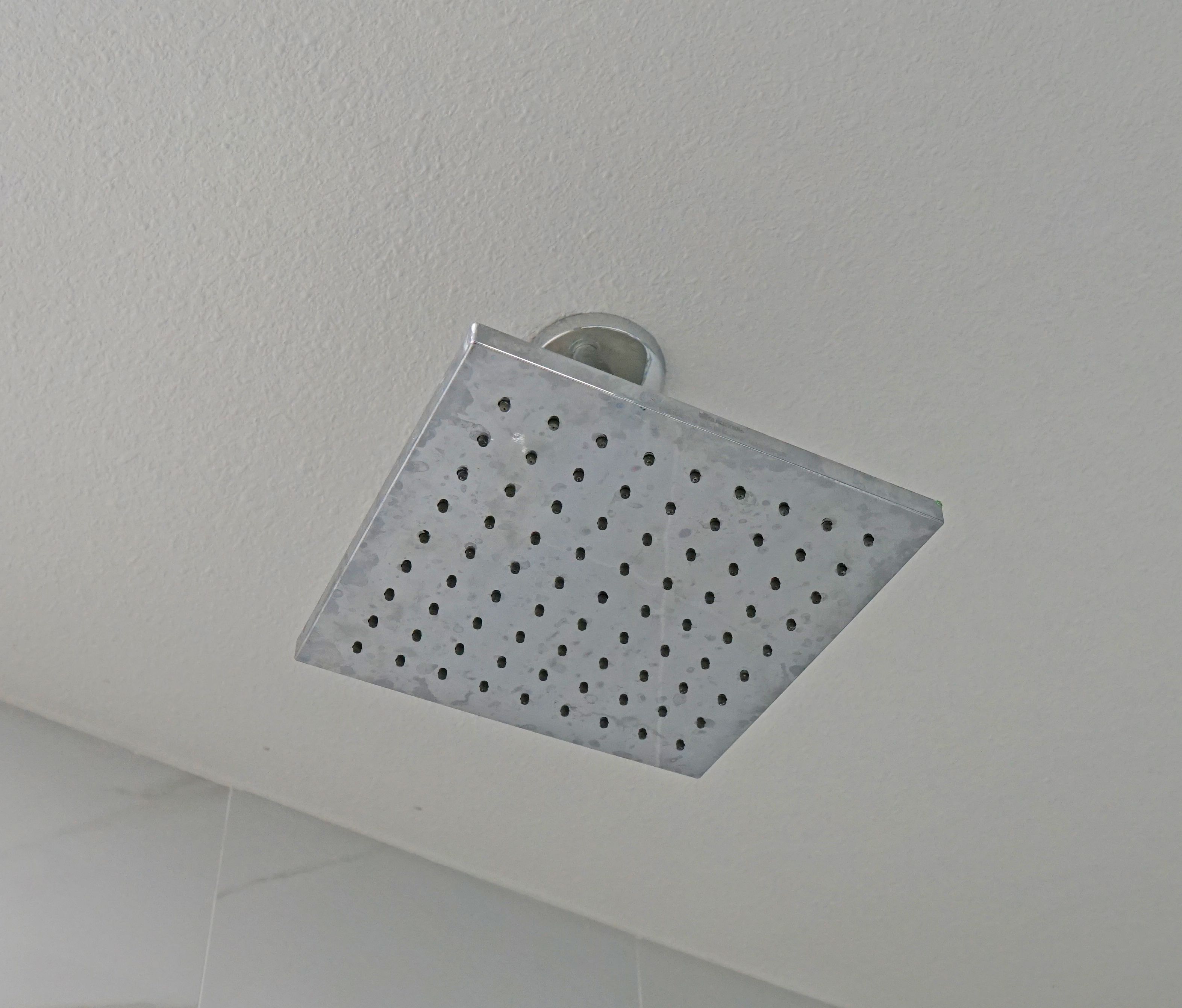 A ceiling-mounted, square, perforated light fixture with a handle.