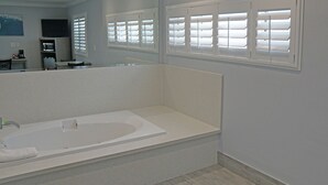 A modern bathroom with a large bathtub, a shower area, and a vanity with a mirror. - Surf City Inn - Near Seal Beach Pier (Seal Beach)