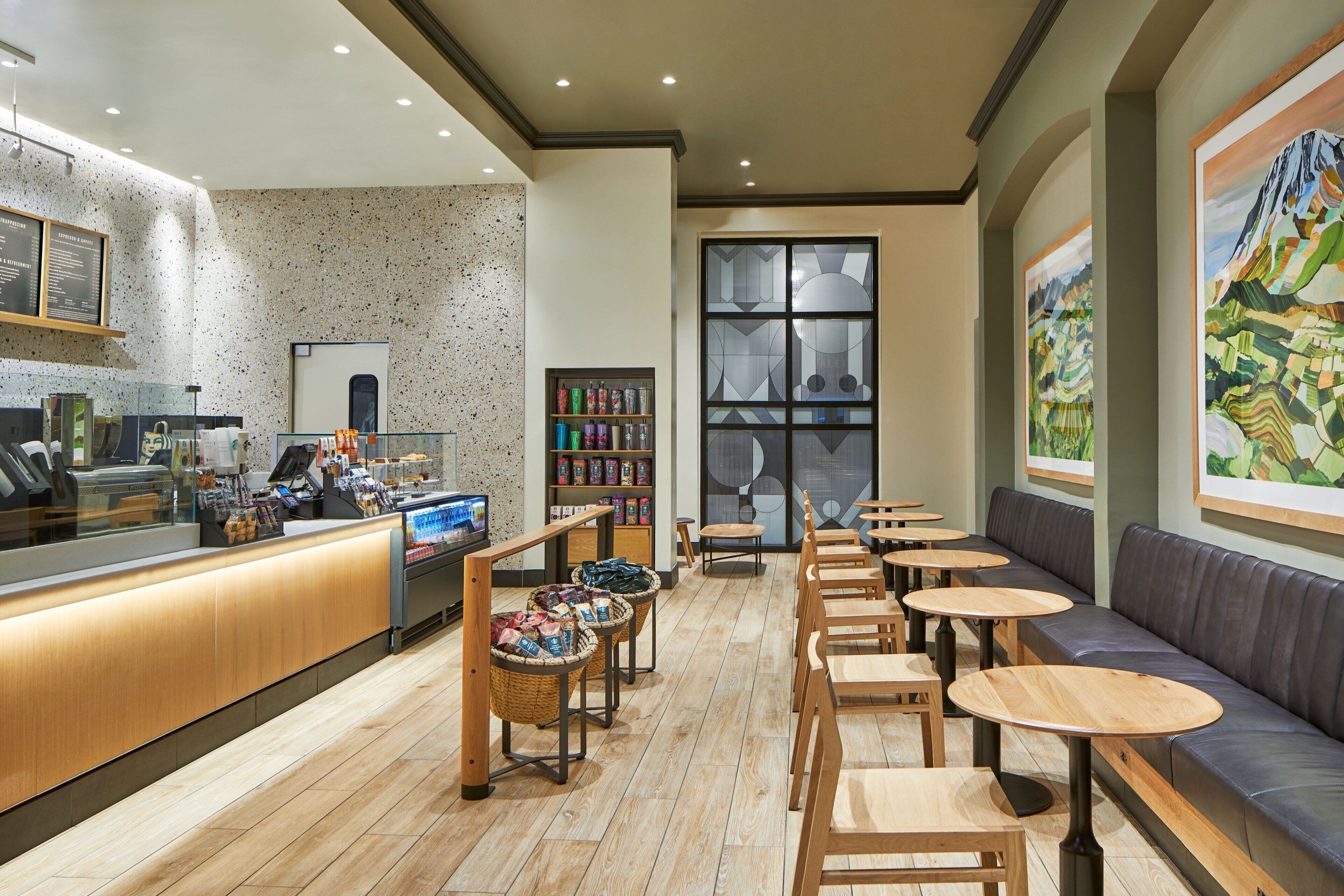A café with a wooden counter, seating area, and artwork on the walls.