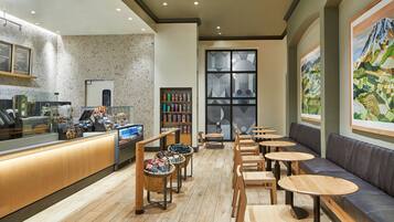A café with a wooden counter, seating area, and artwork on the walls.
