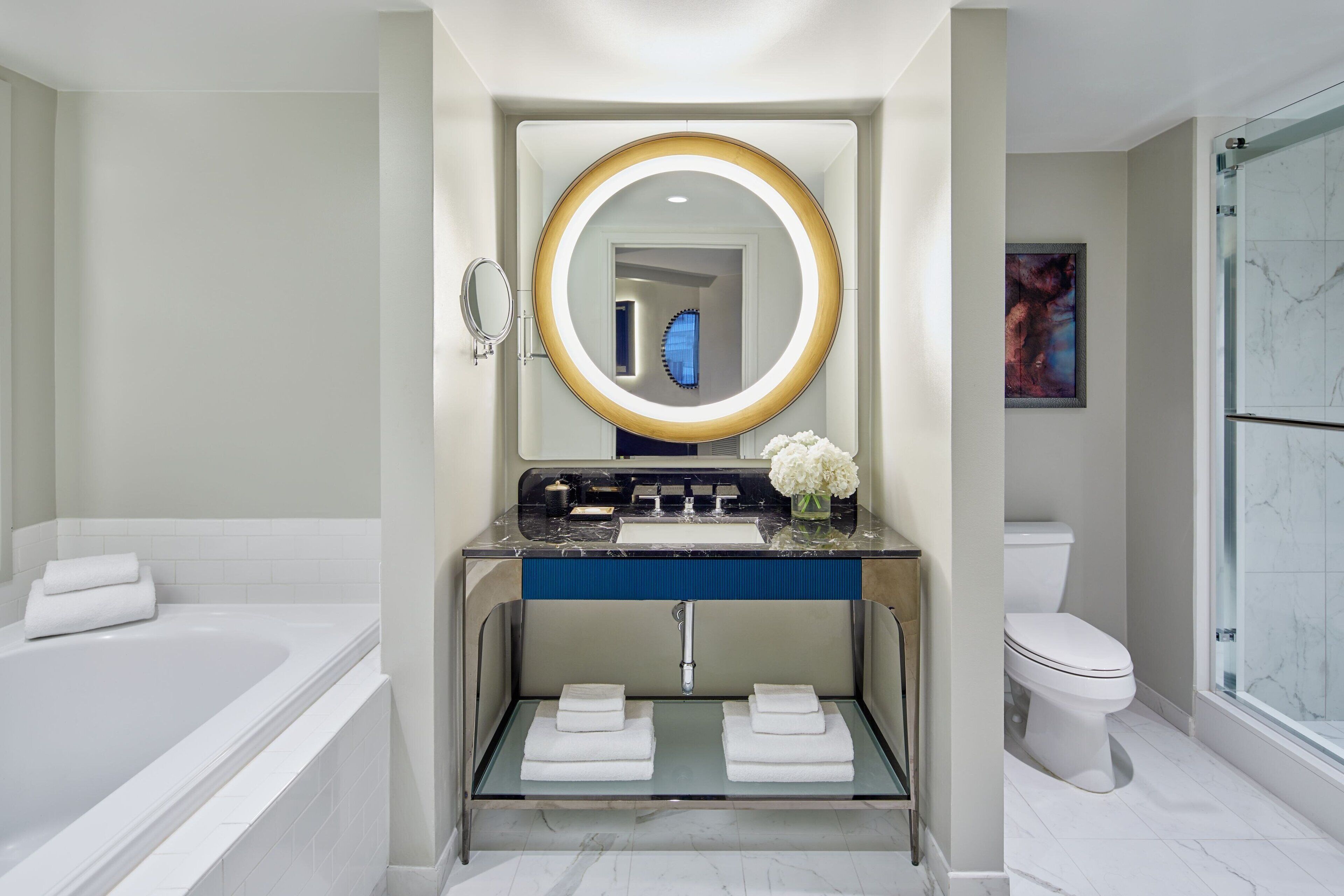 Une salle de bain moderne avec une baignoire, un meuble-lavabo avec un miroir, des toilettes et une douche en verre.