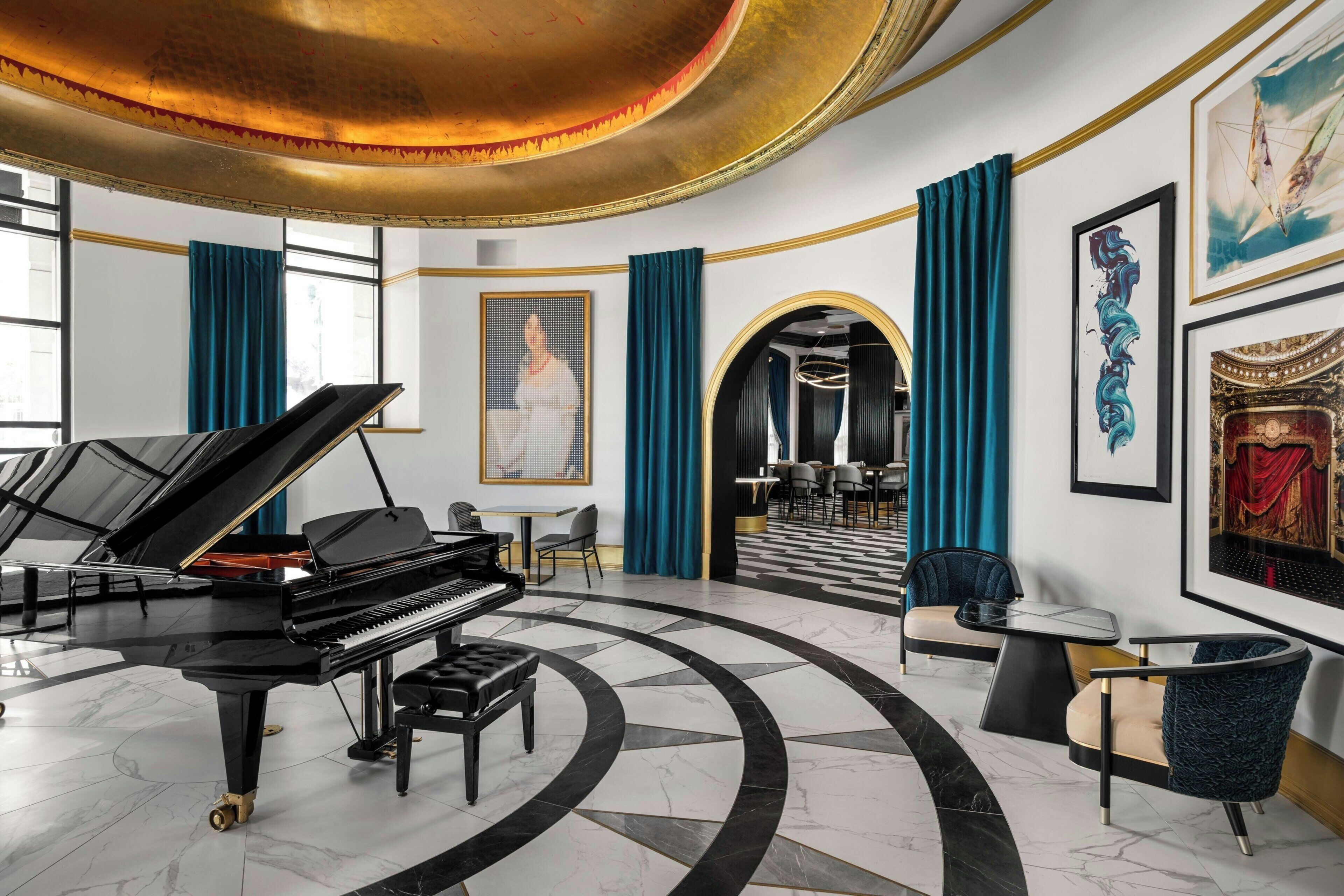 A grand piano in a spacious room with a marble floor, a dining area with chairs, and a large window.
