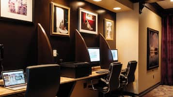 A conference room with three computer monitors, a laptop, and a printer on a desk.