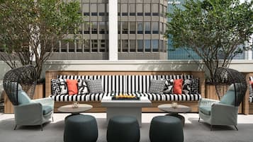 Eine Dachterrasse mit einer schwarz-weißen Streifenliege, zwei Sesseln und einem Couchtisch in der Mitte.