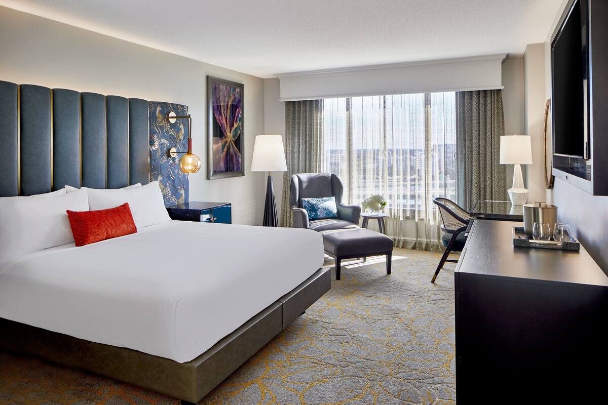 Une chambre d’hôtel avec un grand lit, un bureau, une chaise et une vue sur la ville.